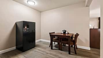 A compact kitchen with a black refrigerator, wooden dining table, and chairs.