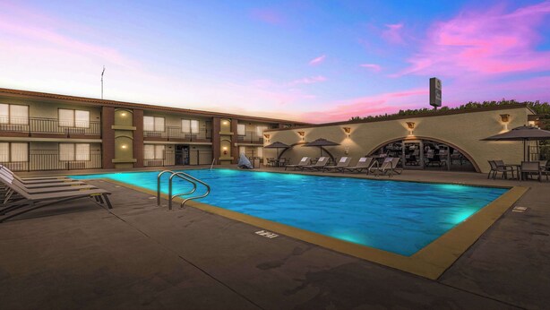 A hotel with a swimming pool, lounge chairs, and a covered seating area. - Best Western Roseville Inn (Roseville)
