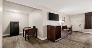 A compact hotel room with a kitchenette, a dining area, a desk, and a flat-screen TV. - Best Western Roseville Inn (Roseville)