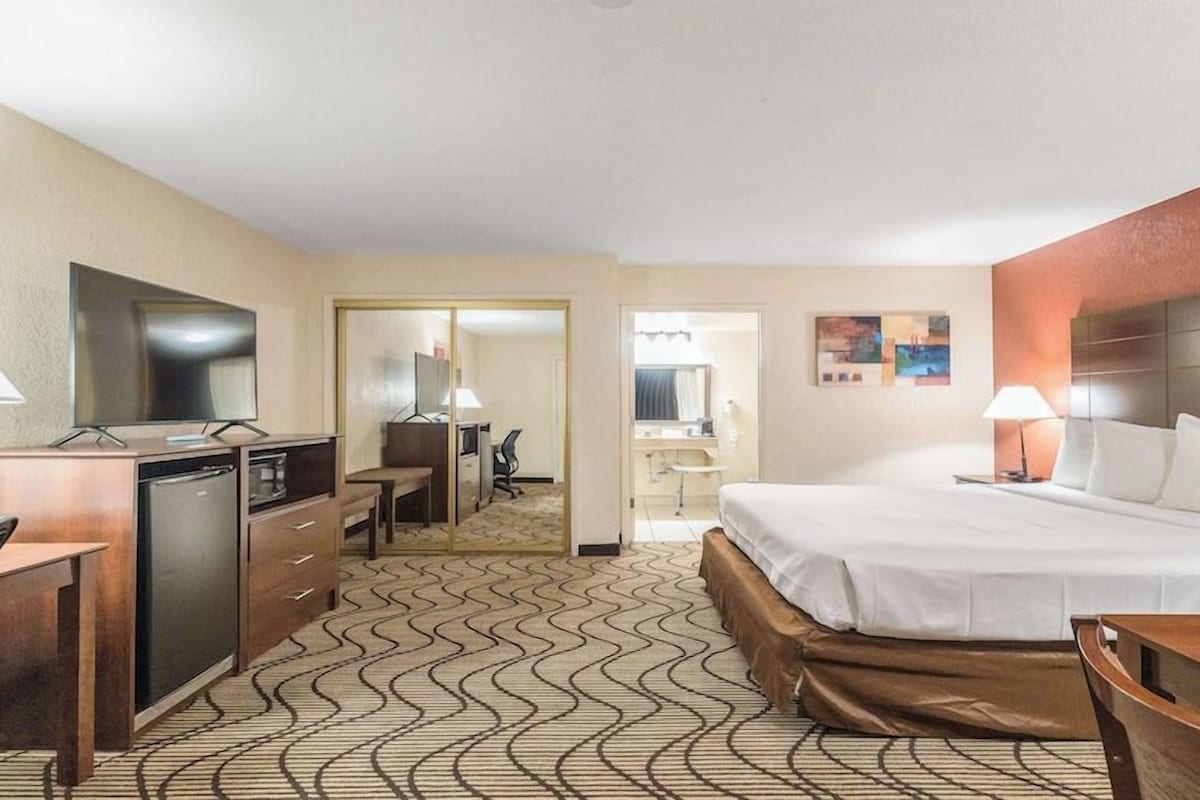 Une chambre d’hôtel équipée d’un lit, d’un bureau, d’une chaise et d’un miroir.