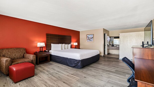 A hotel room with a bed, a chair, a desk, and a bathroom visible through an open door. - Best Western Roseville Inn (Roseville)