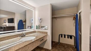 A bathroom with a sink, mirror, hairdryer, and shower curtain.