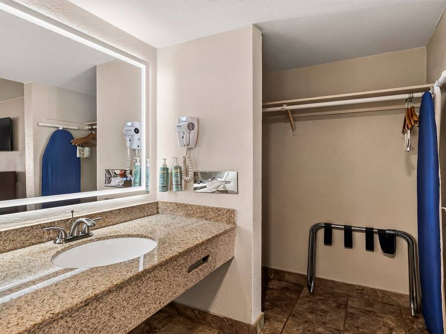 A bathroom with a sink, mirror, hairdryer, and shower curtain.