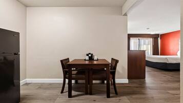 A compact room with a dining table, chairs, a bed, and a kitchenette.