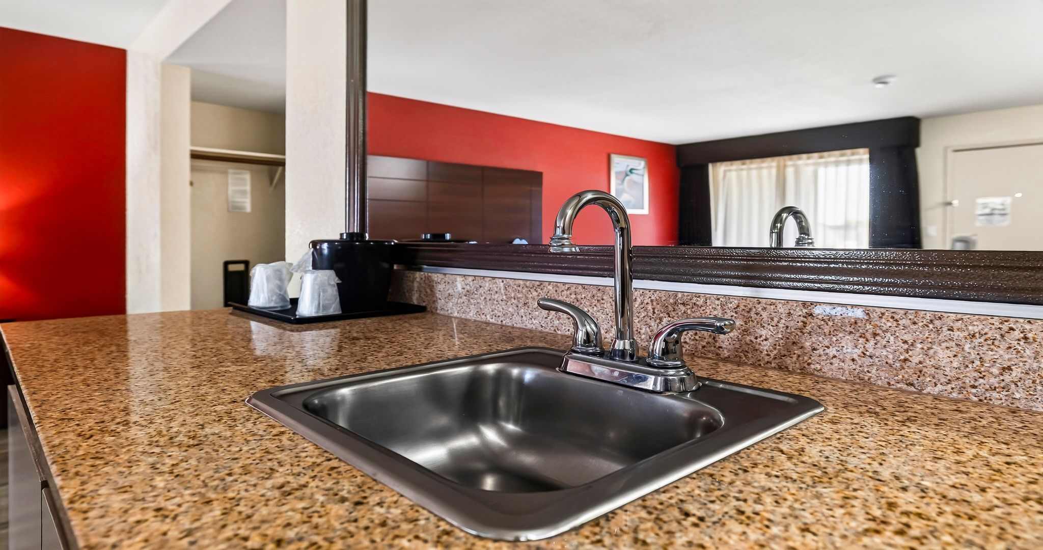 A modern kitchen with a granite countertop, stainless steel sink, and a double faucet.