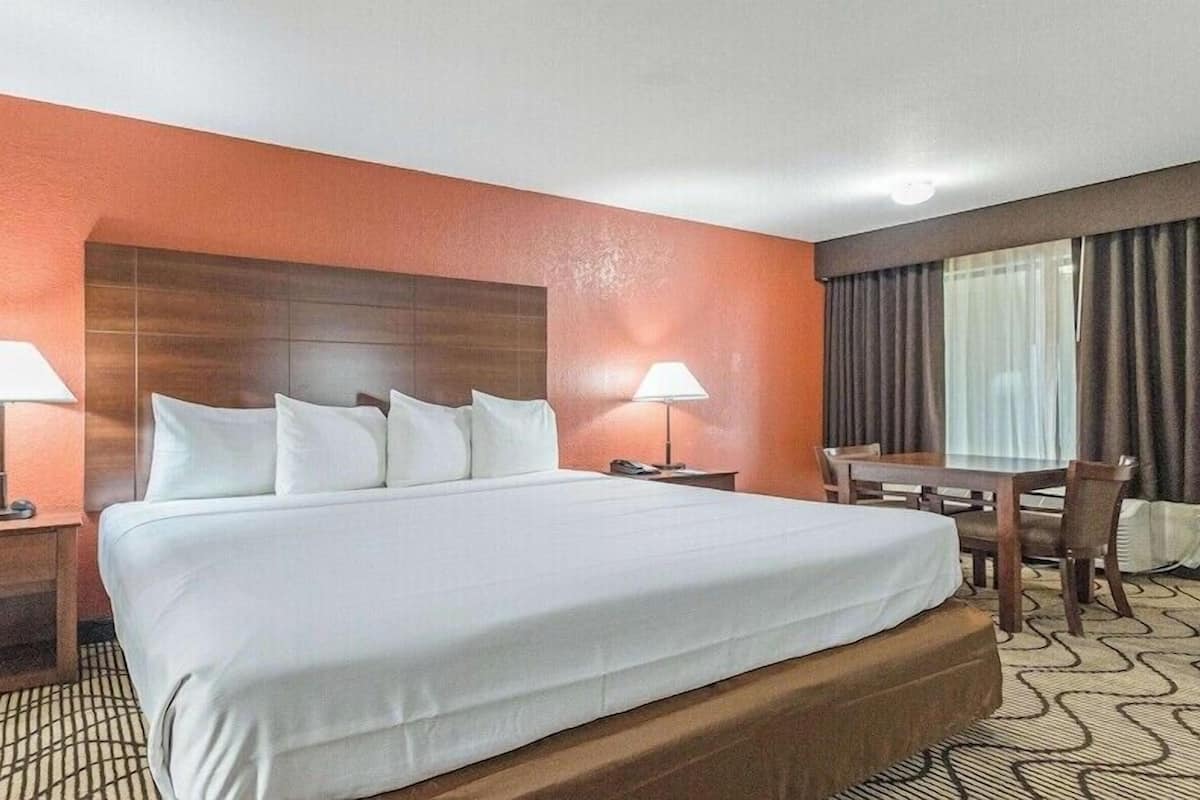 Ein Hotelzimmer mit einem großen Bett, zwei Nachttischen, einem Schreibtisch und einem Sessel.