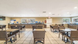 A spacious dining area with multiple tables and chairs, a counter with a menu, and a view of the outside through large windows. - Best Western Roseville Inn (Roseville)