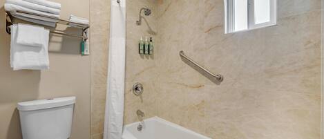 A bathroom with a toilet, a bathtub, a shower, and a window.