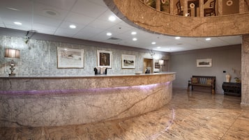 A marble reception desk with framed pictures, a bench, and a decorative vase.