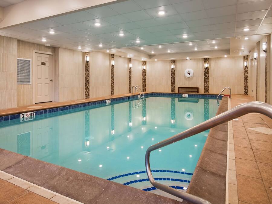 An indoor swimming pool with clear water, a tiled floor, and a metal handrail.