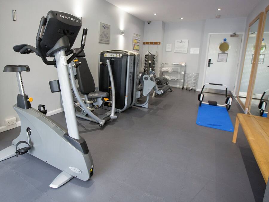 A gym with cardio machines, weight training equipment, and a mirror.