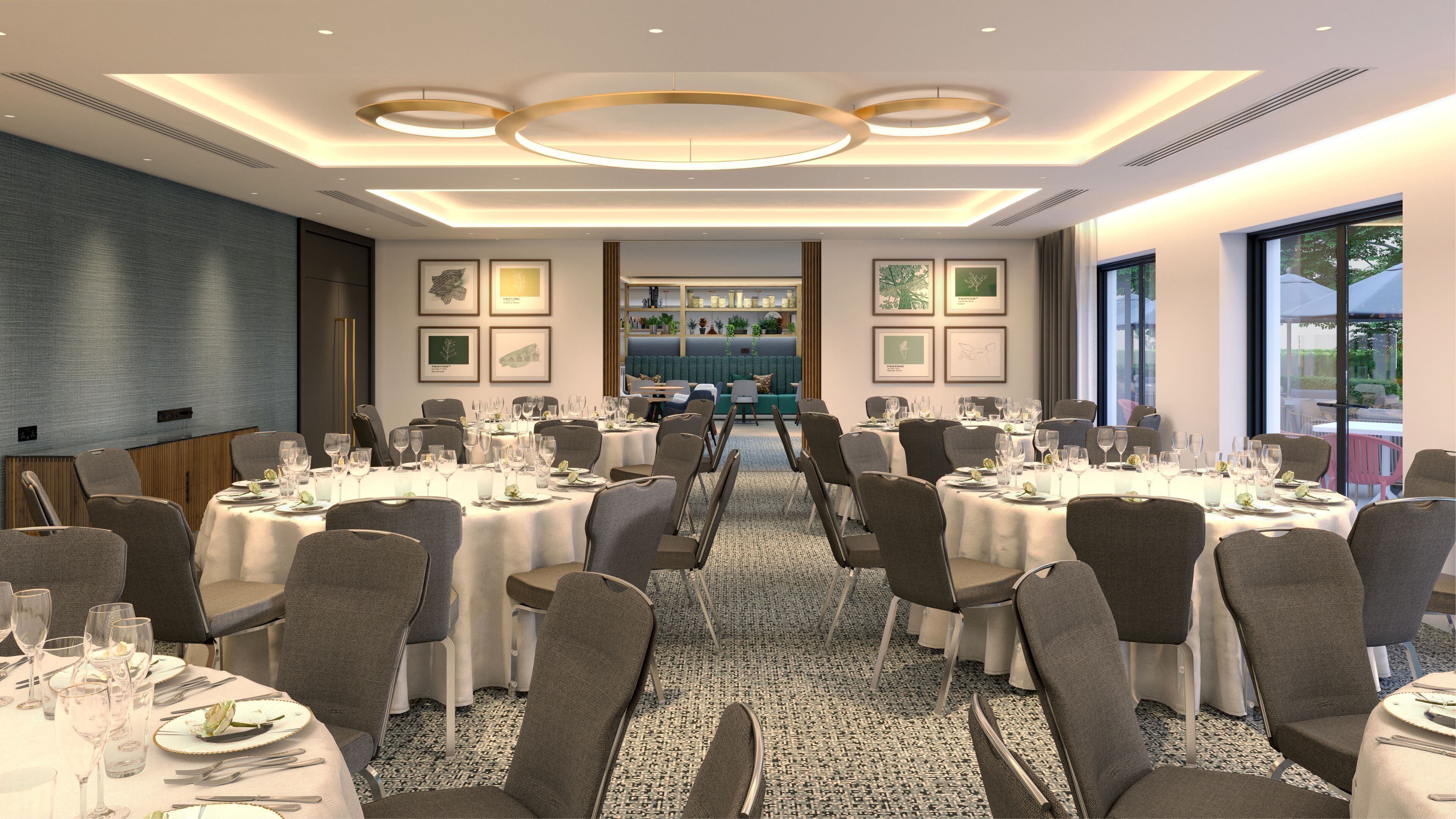 A spacious dining area with round tables, grey upholstered chairs, and a view of a garden through a large window.