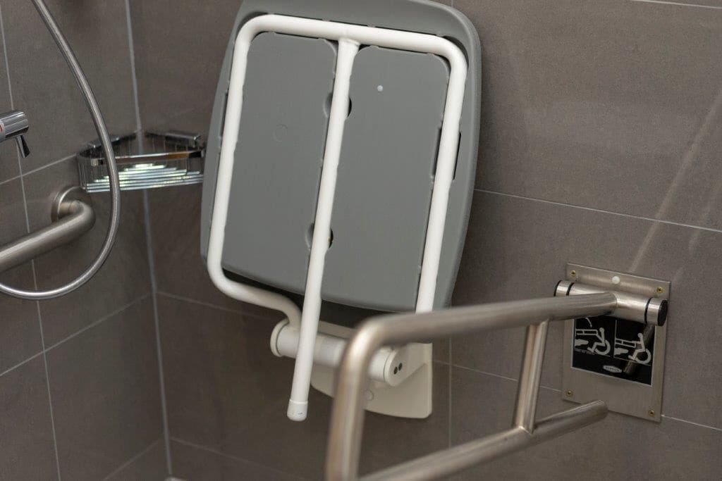 Un espace douche équipé d’une barre d’appui et d’une main courante.