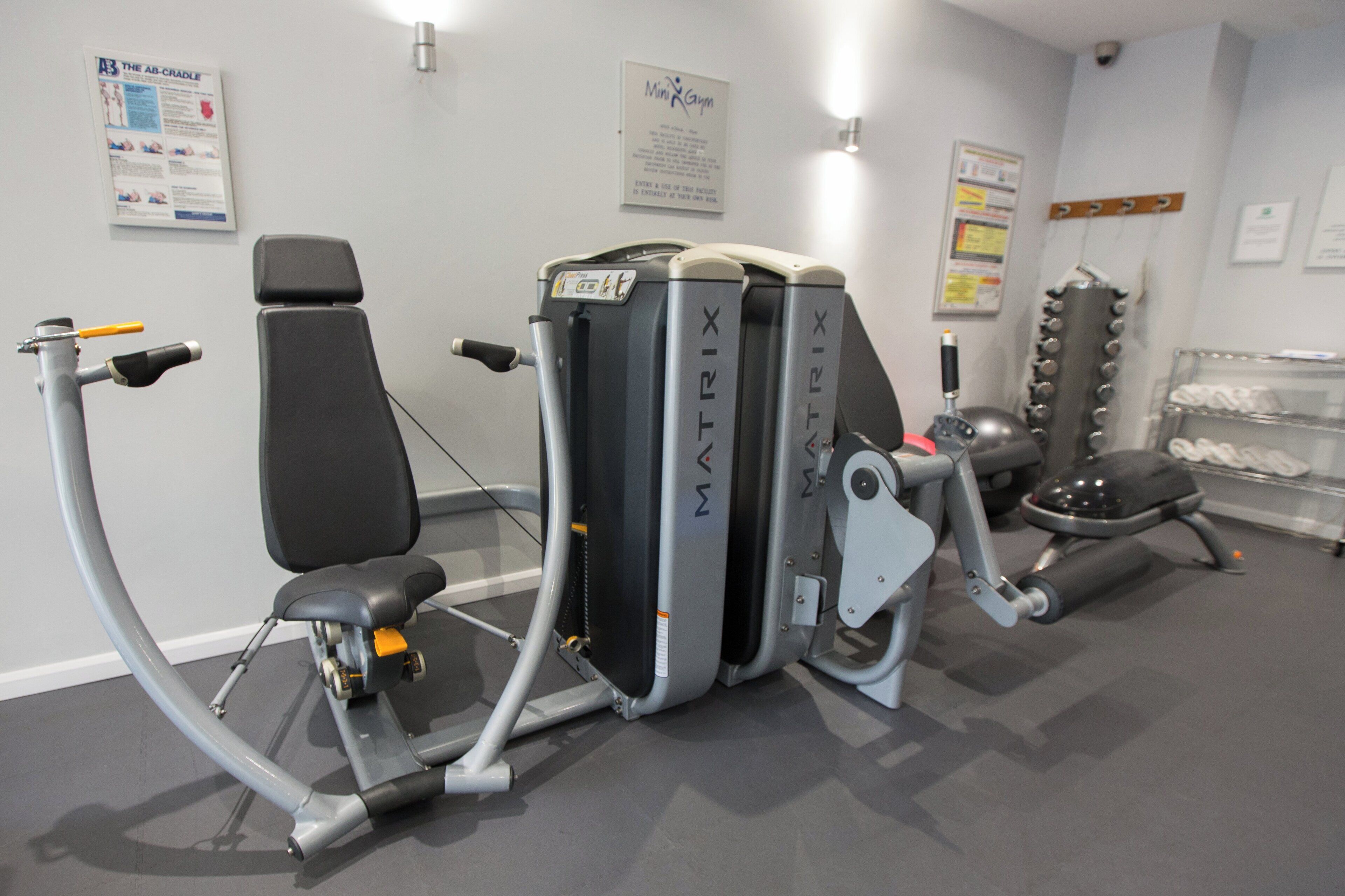 Un gimnasio con equipo de ejercicio que incluye una máquina de remo, una bicicleta estática y una prensa de piernas.