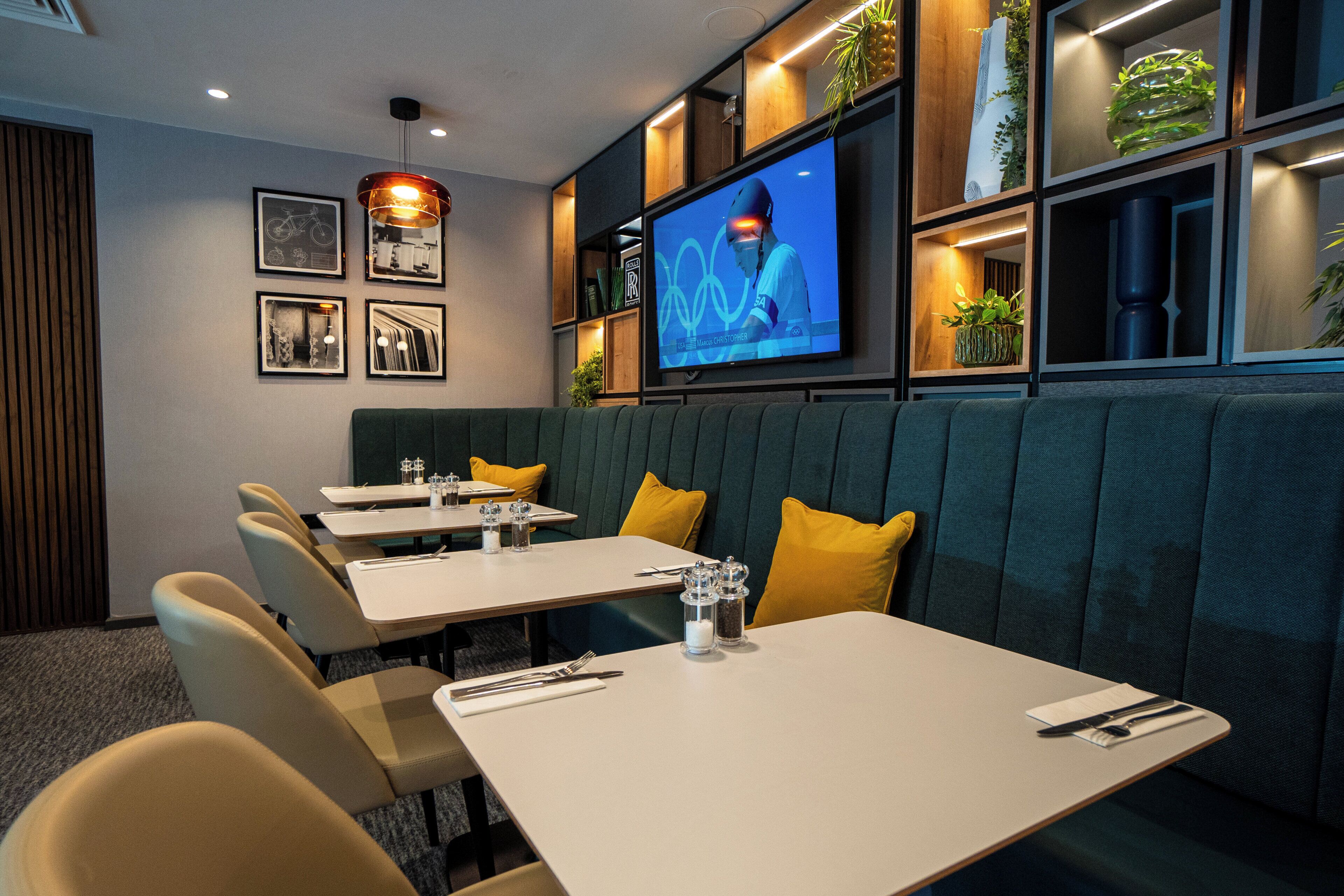 A restaurant with booths, tables, and a TV screen displaying a sports event.