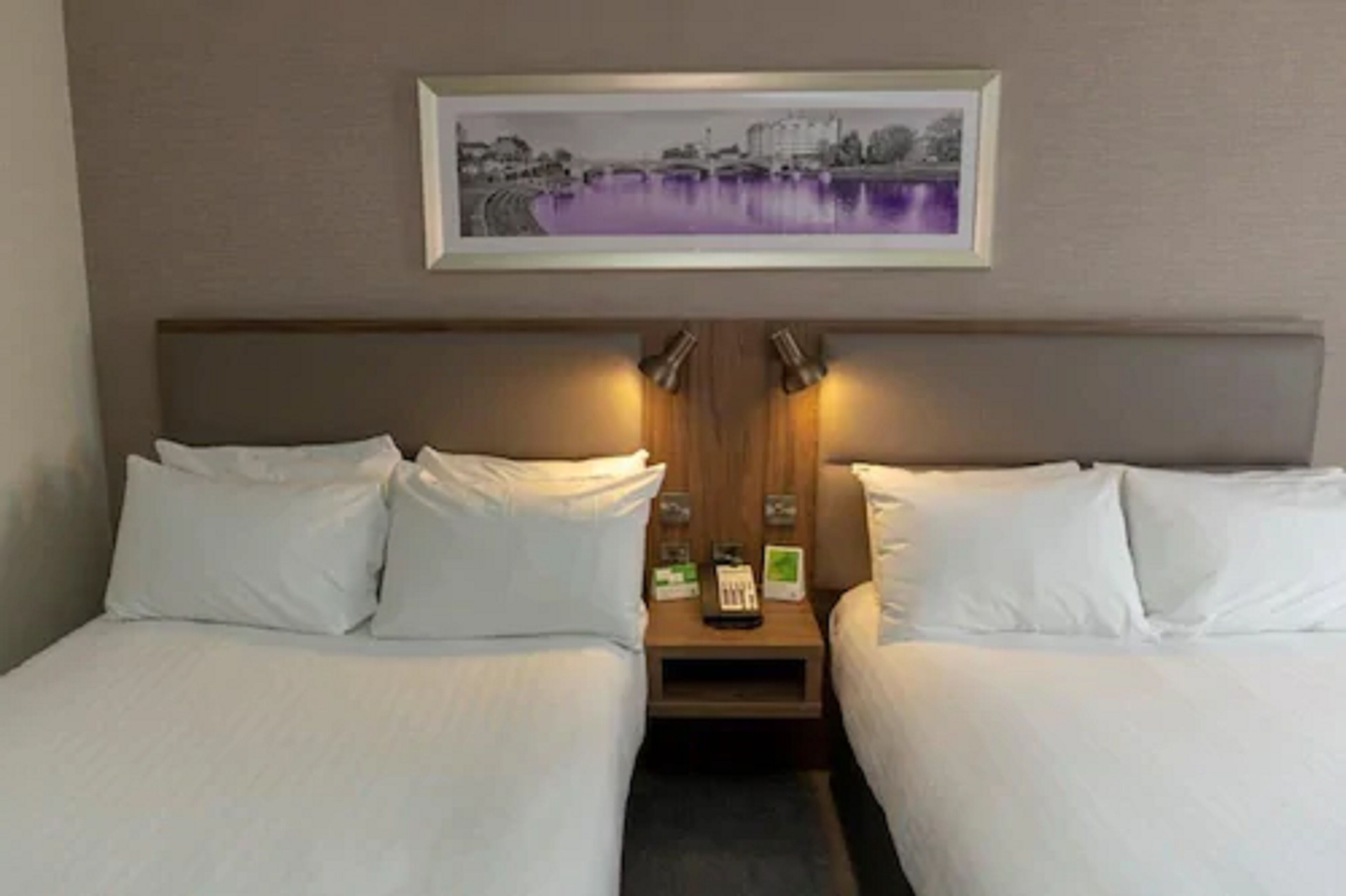 A hotel room with two beds, a framed picture on the wall, and bedside lamps.
