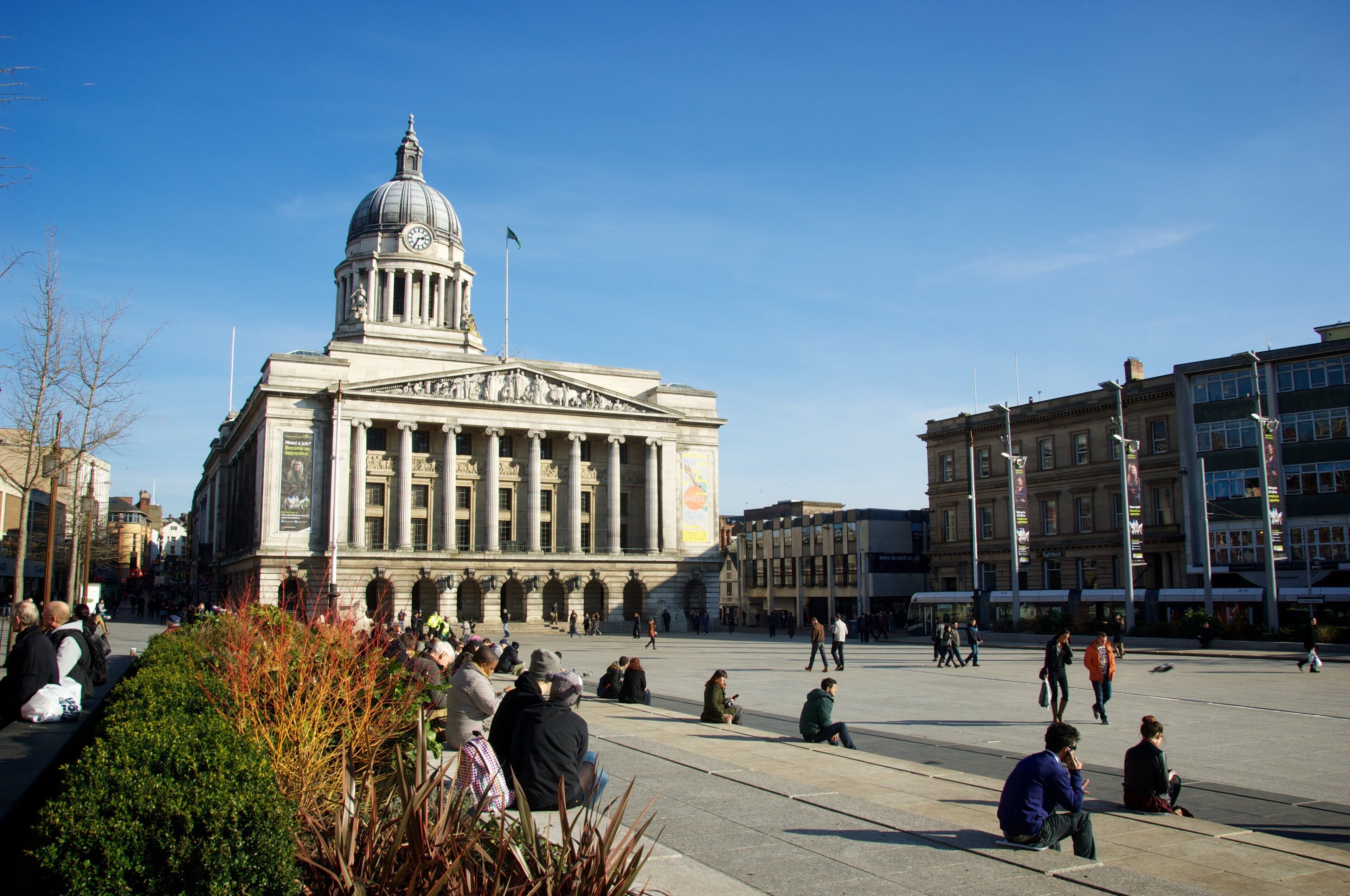 A large public square with a prominent neoclassical building featuring a dome and columns.