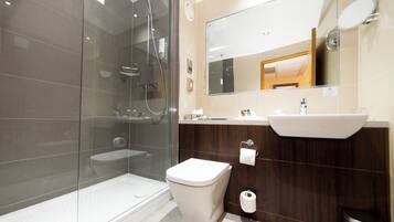A modern bathroom with a glass-enclosed shower, a white toilet, and a vanity with a mirror and sink.