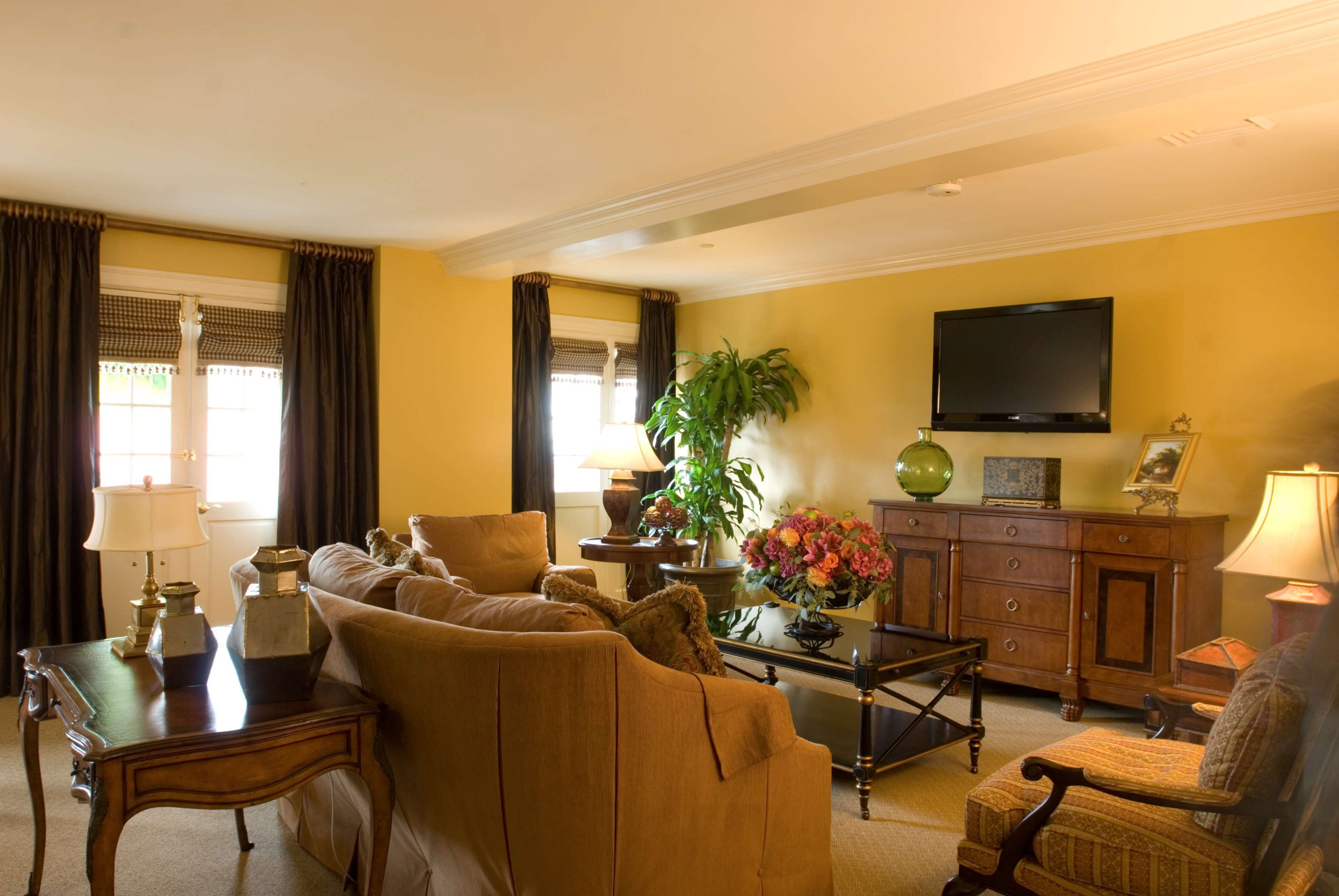 A living room with a sofa, armchairs, a coffee table, a TV, and a plant.