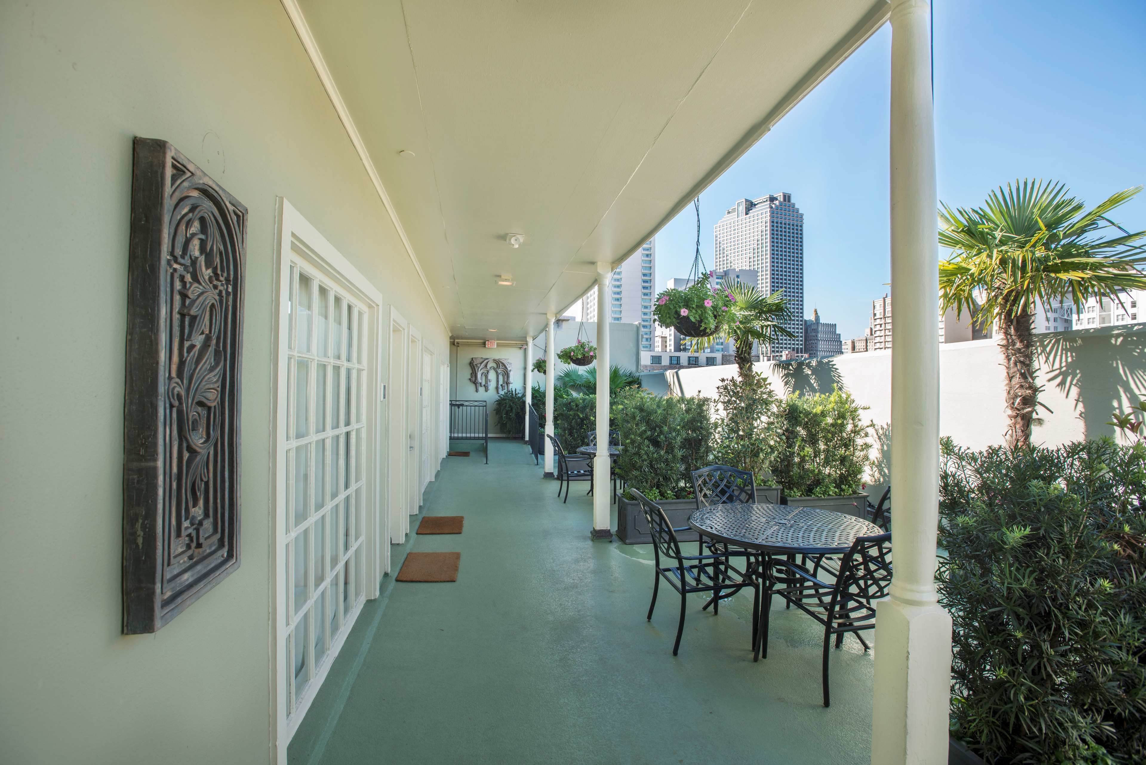 A covered outdoor area with a table and chairs, a decorative wall piece, and a view of tall buildings in the background.