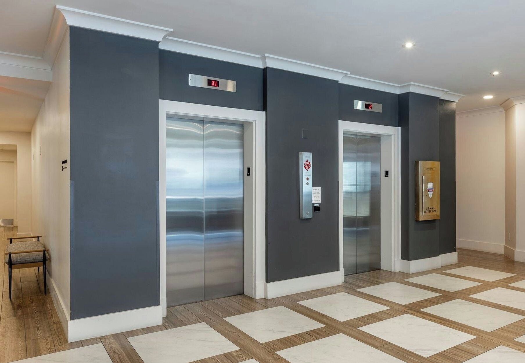 A modern elevator with a digital display, a US mail letterbox, and a patterned floor.
