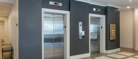 A modern elevator with a digital display, a US mail letterbox, and a patterned floor.