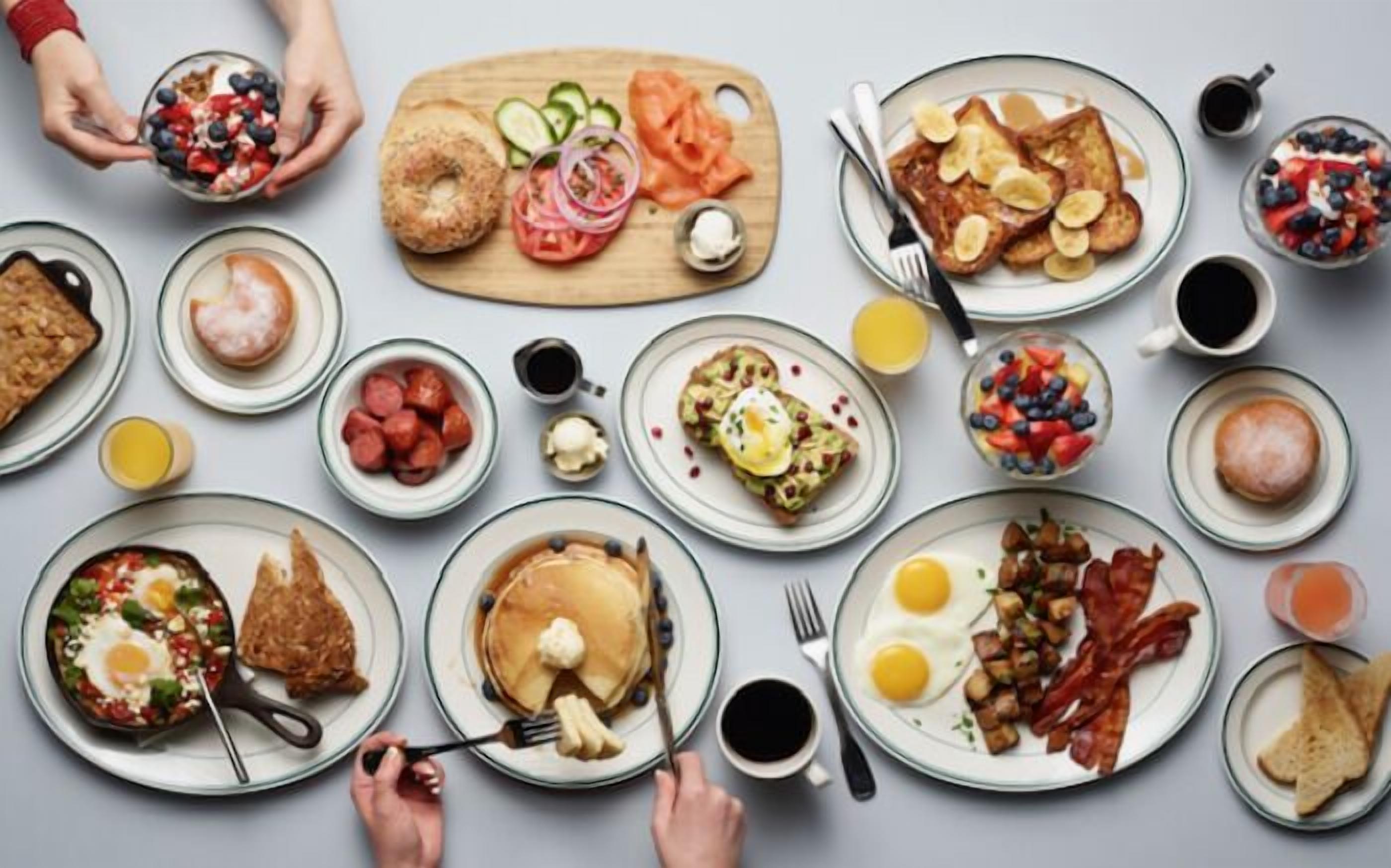 A breakfast buffet with various dishes including eggs, bacon, pancakes, and fruit.