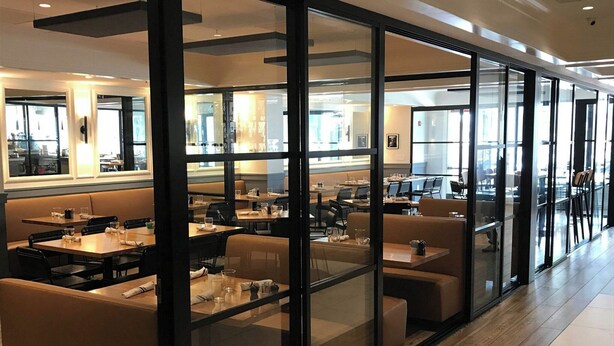 A modern dining area with glass partitions, wooden flooring, and a variety of seating options. - The Georgetown Inn (Washington)