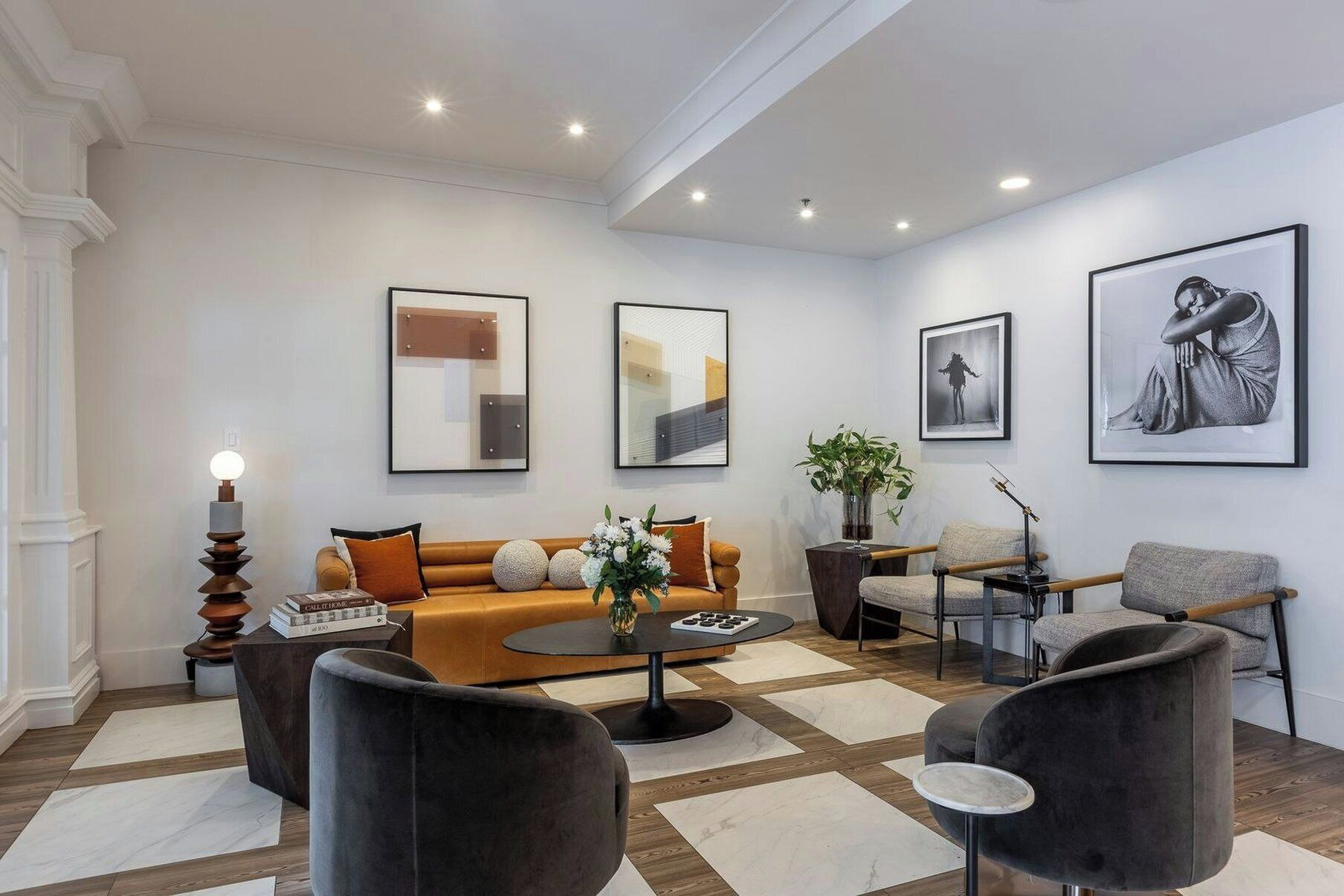 Un salon moderne avec un canapé, des fauteuils, une table basse et des œuvres d’art accrochées aux murs.