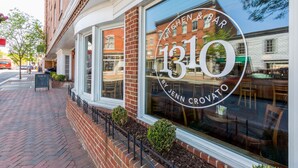 Een restaurant met een groot raam waarop de naam 'Kitchen & Bar 1310 by Jenn Crovato' staat.
