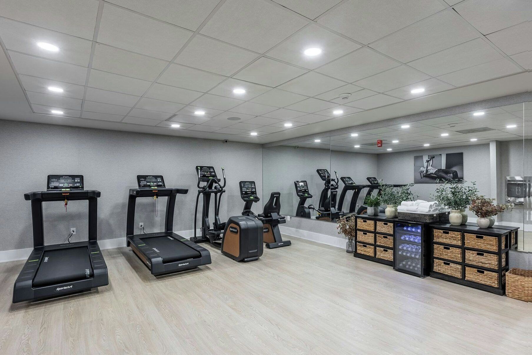 A gym with multiple treadmills, stationary bikes, and a mirrored wall.
