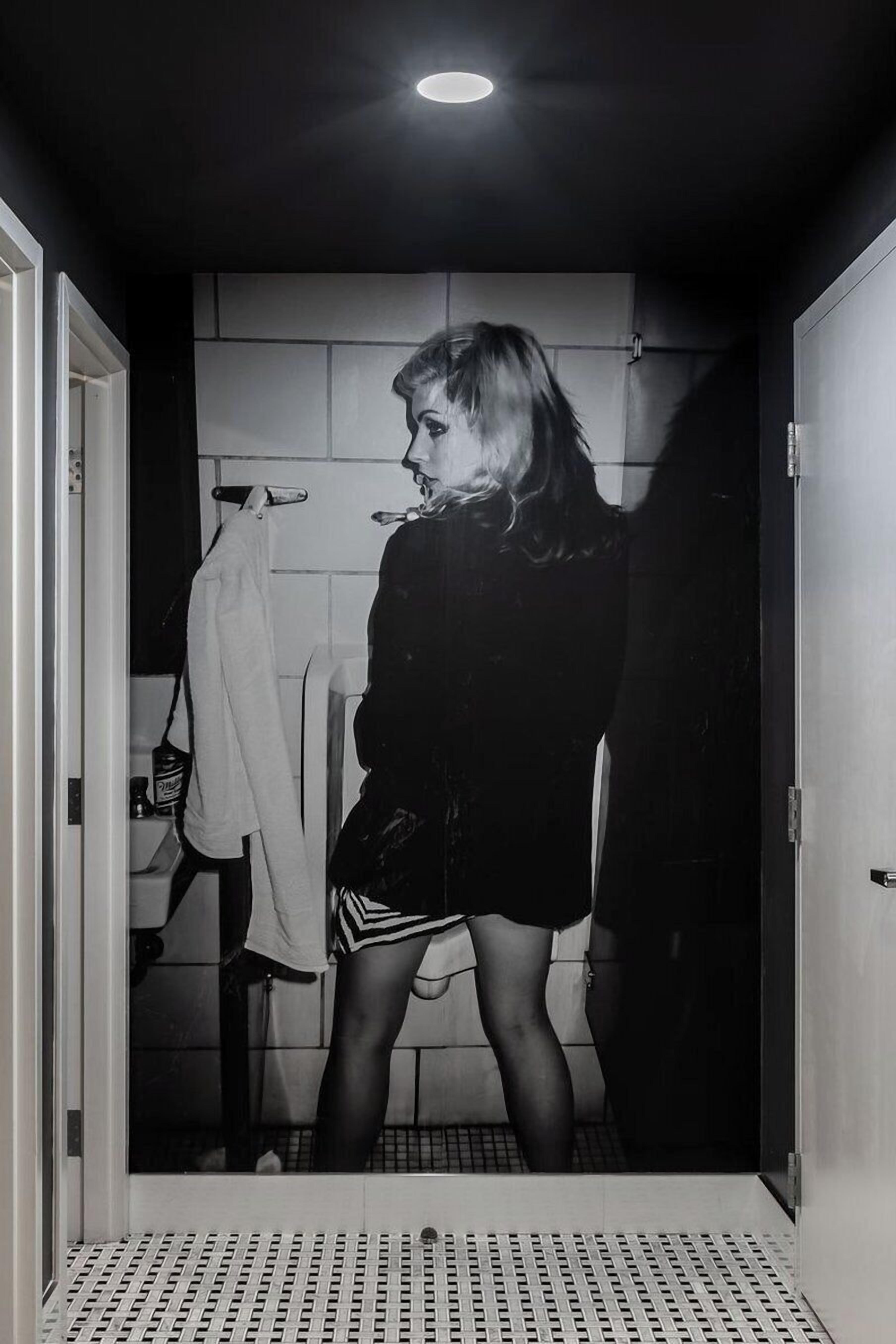 A person standing in a bathroom with a tiled wall, a shower curtain, and a towel rack.