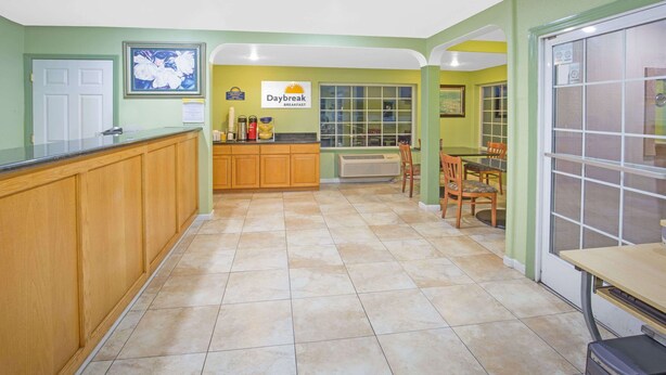 Uma cozinha com placa de café da manhã, armários de madeira, piso ladrilhado e uma área de jantar com cadeiras e mesa.