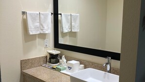 Uma casa de banho de hotel com uma pia branca, um espelho grande e duas toalhas penduradas em ganchos.