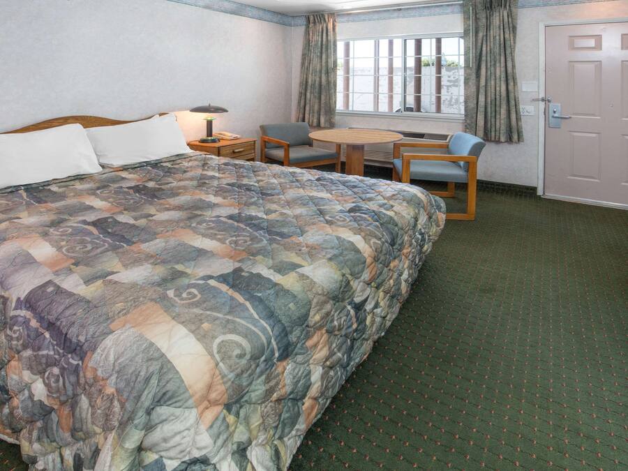 Una camera d'albergo con un letto grande, una scrivania con una sedia, un tavolino e una finestra con tende.