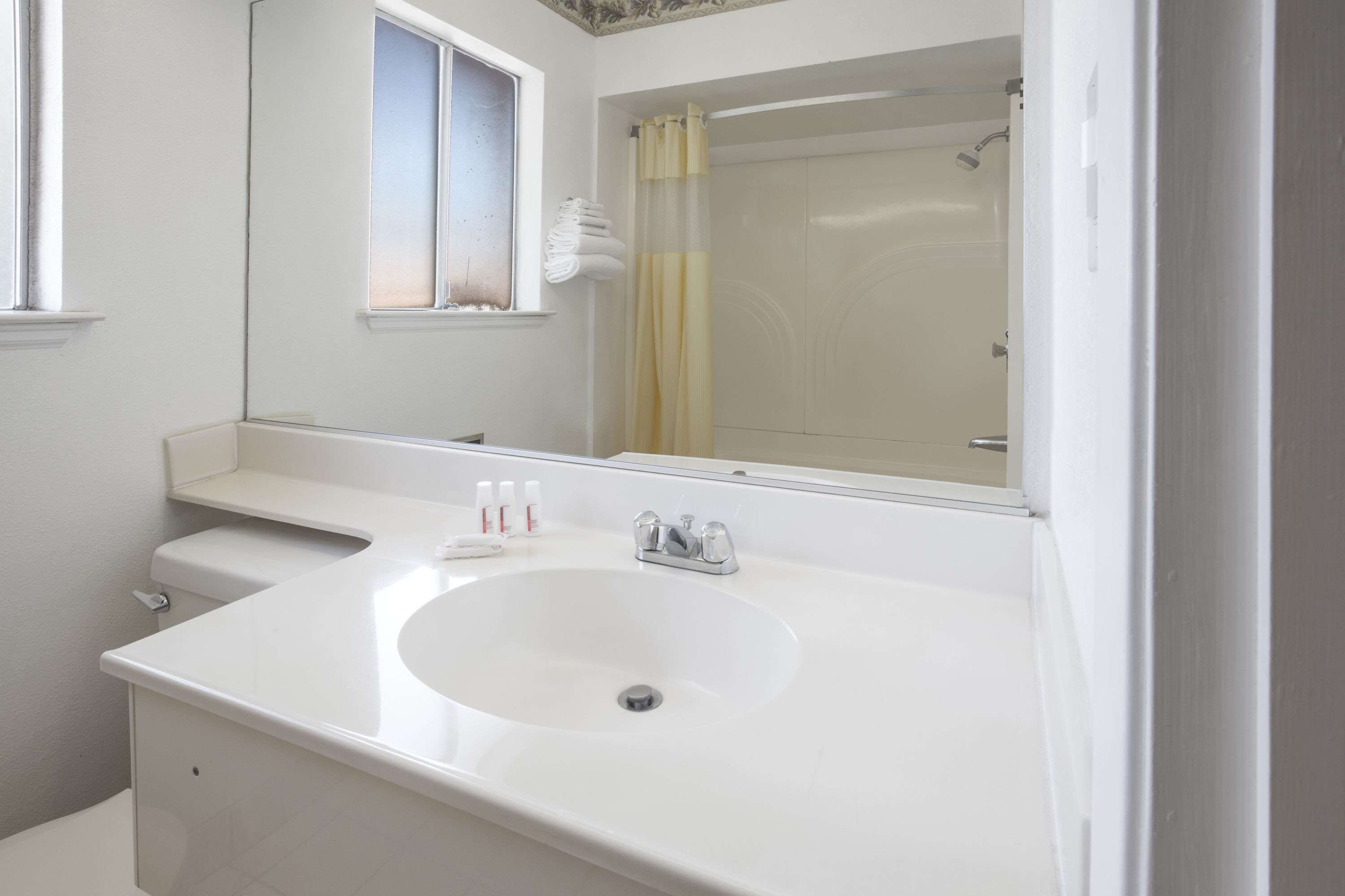 A bathroom with a white sink, mirror, and shower.