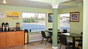 Espaço de café da manhã com uma placa indicando "Daybreak Breakfast", armários de madeira, um espaço para café e vista para o exterior.