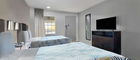 Een hotelkamer met twee bedden, een televisie, een bureau en een raam met gordijnen.