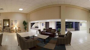 A spacious lobby with a curved ceiling, a central seating area with sofas and a coffee table, and a large potted plant. - Holiday Inn Express Little Rock Airport by IHG (Little Rock)