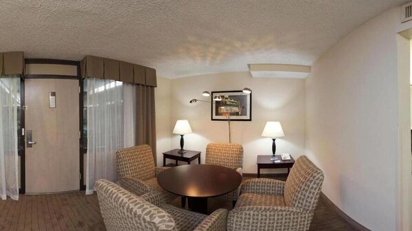 A hotel room with a round table, two armchairs, a sofa, a door, and a framed picture on the wall. - Holiday Inn Express Little Rock Airport by IHG (Little Rock)