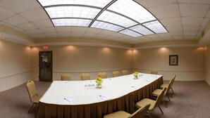 A conference room with a large oval table, beige chairs, a glass ceiling, and a framed picture on the wall. - Holiday Inn Express Little Rock Airport by IHG (Little Rock)