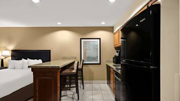 A hotel room with a bed, a desk, a chair, a television, and a refrigerator.