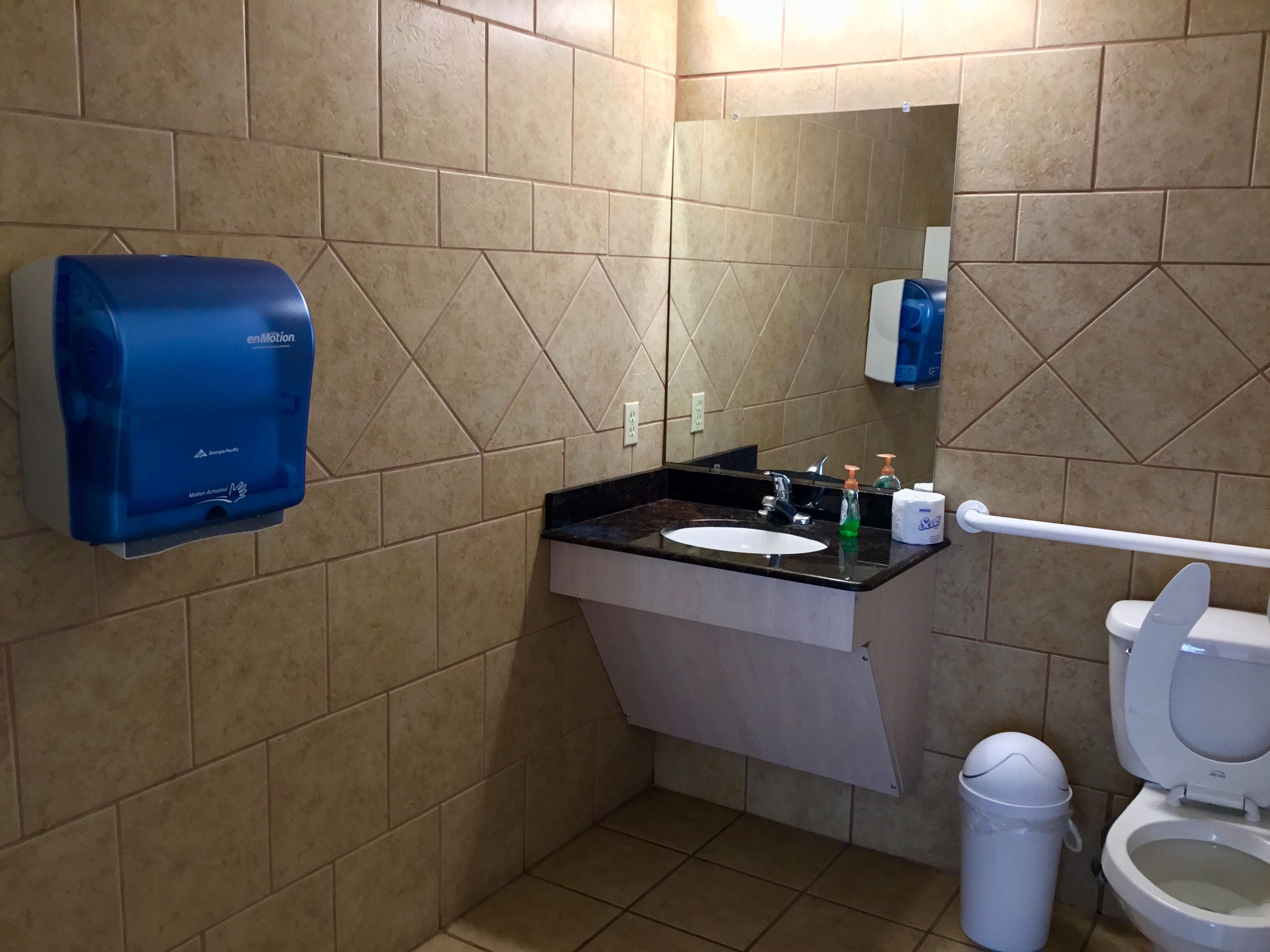 A bathroom with a sink, mirror, toilet, and hand dryer.