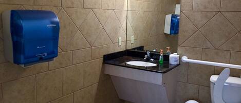 A bathroom with a sink, mirror, toilet, and hand dryer.