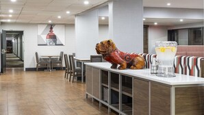 A modern hotel lobby with a reception desk, seating area, and a large wall mural. - Hampton Inn Athens (Athens)