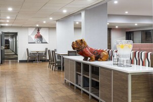 A modern hotel lobby with a reception desk, seating area, and a large wall mural.