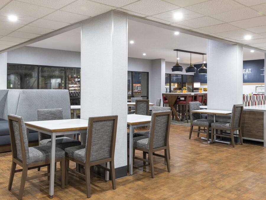 Un restaurante moderno con mesas altas, cabinas, suelo de madera y una zona de bar.