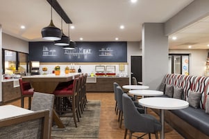 A modern cafe with a central bar, seating area, and a chalkboard menu.