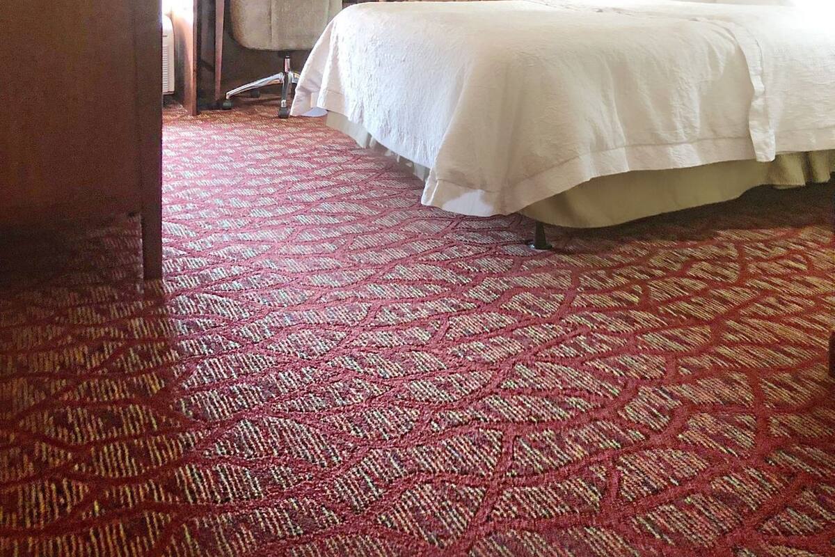 A hotel room with a bed, desk, chair, and wardrobe.