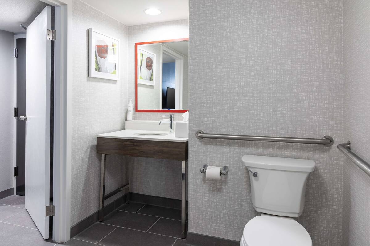 A modern bathroom with a toilet, sink, and mirror.